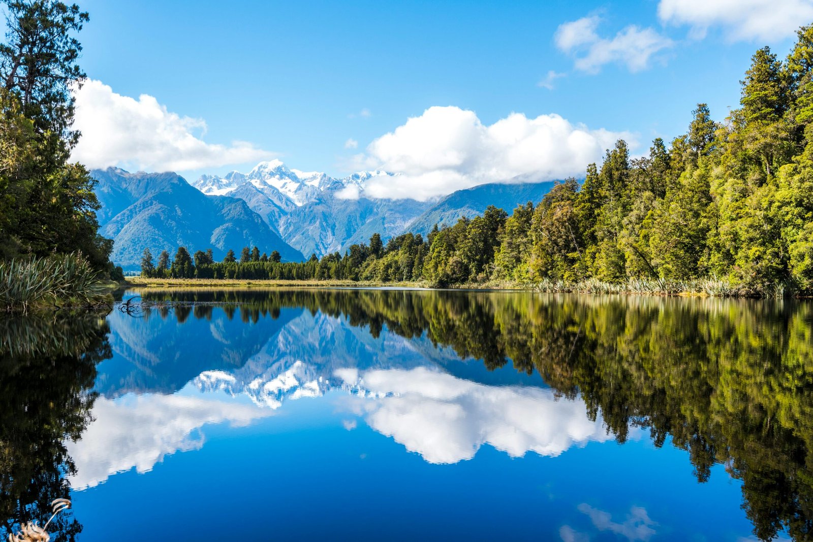 Peaceful mountain lake with stunning reflections and surrounding forest on a clear day.